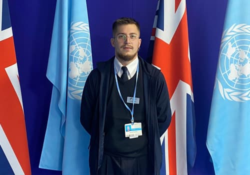 A K1 officer standing in front of Union Jack and United Nations flags