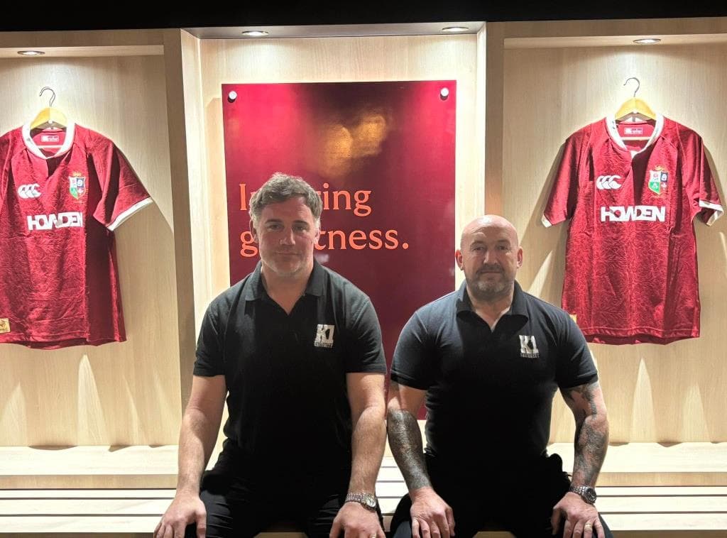 Stephen Pape and Martin Barrington in K1 shirts, seated in a changing room